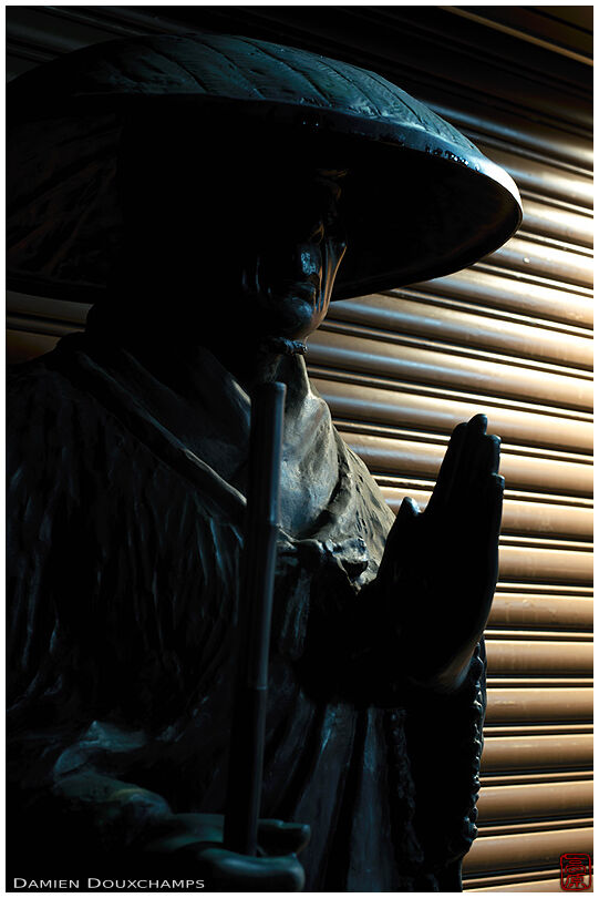 Pilgrim statue in front of store shutter, Kyoto, Japan