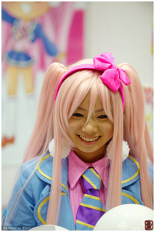 Cosplaying young woman with pink hair during the crafts expo at the Tokyo Big Sight conference center, Tokyo, Japan