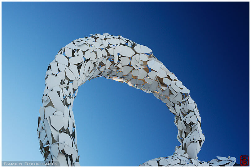 White metallic arch sculpture on blue sky