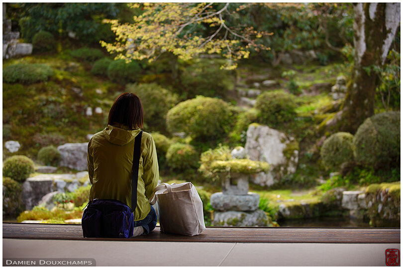 Woman with light green coat color matching the Jikko-in temple's garden spring, Kyoto, Japan
