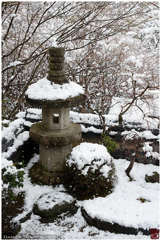 Stone lantern in the snow covered garden of Nobotoke-an, Kyoto, Japan