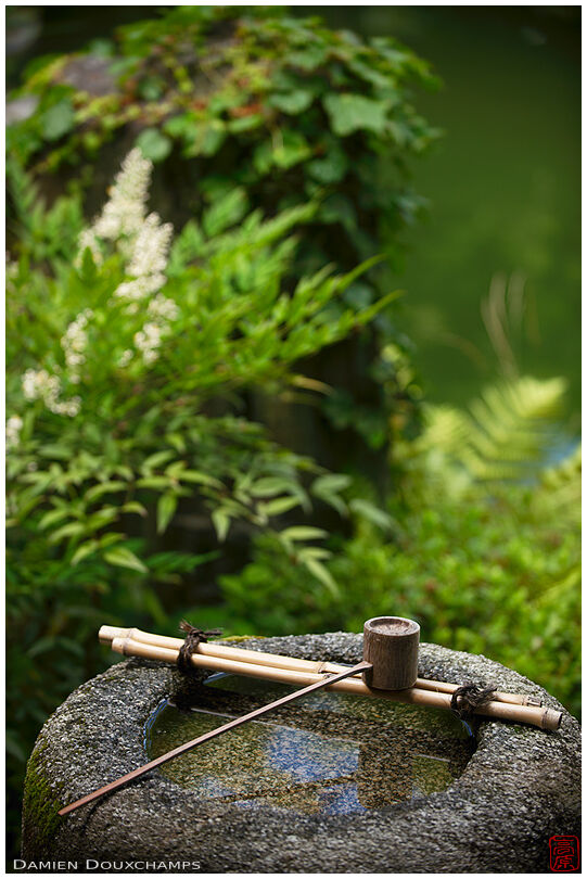 Simple tsukubai water basin with bamboo ladle in the Shusui-tei tea house, Kyoto, Japan