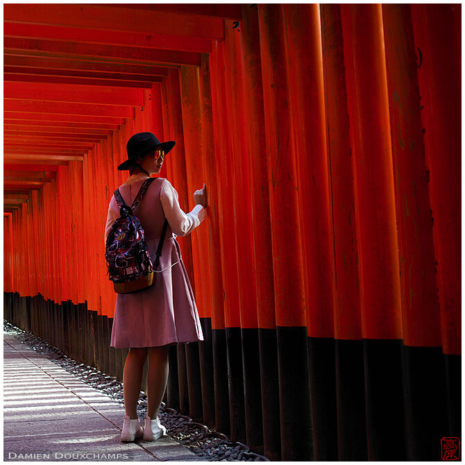 Young woman in red torii tunnel, Fushimi Inari shrine, Kyoto, Japan