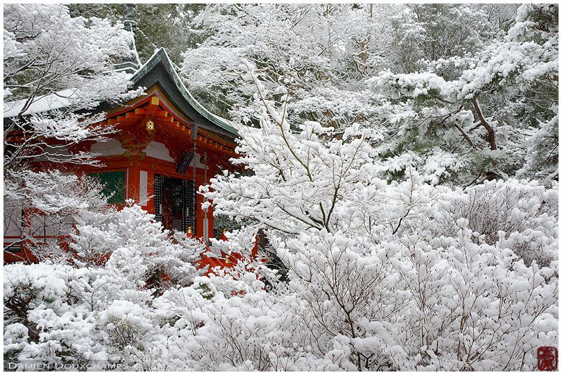 Small red hall lost in snow covered forest, Bishamon-do temple, Kyoto, Japan