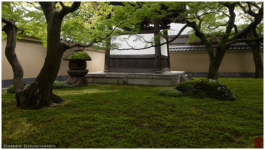Dark stone lantern and belfry in the entrance moss garden of Obai-in temple, Kyoto, Japan