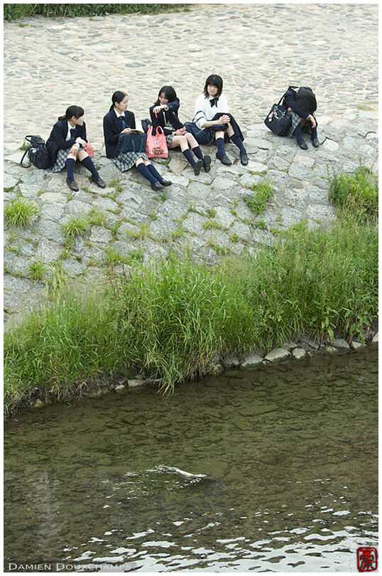 College girls resting along a river after class