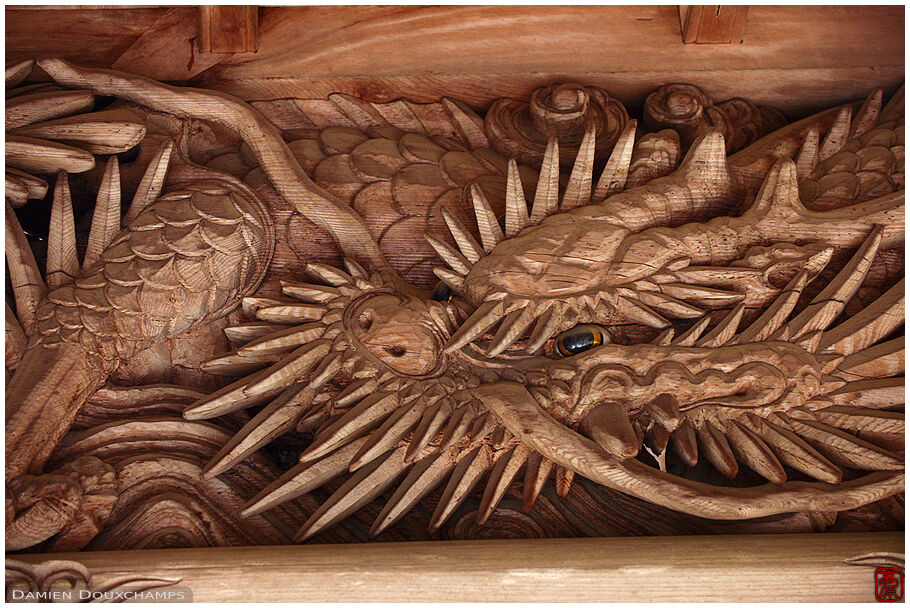 Wooden sculpture of dragon under the gate of a temple