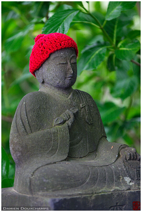 Jizo statue with bright red knitted hat, mount Takao, Tokyo, Japan