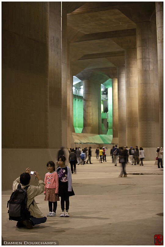Father photographing his two daughters in the massive water retaining underground concrete tank of the G-Cans flood prevention system in Tokyo, Japan