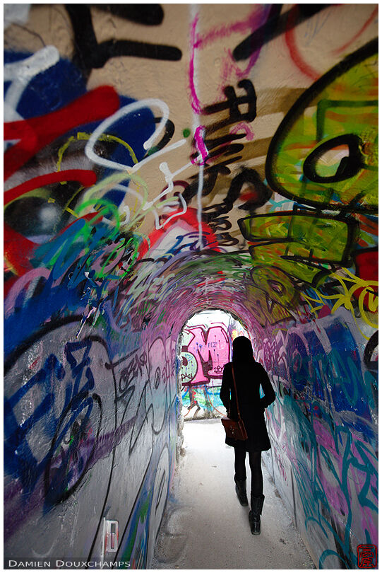 Pedestrian in graffiti-covered tunnel