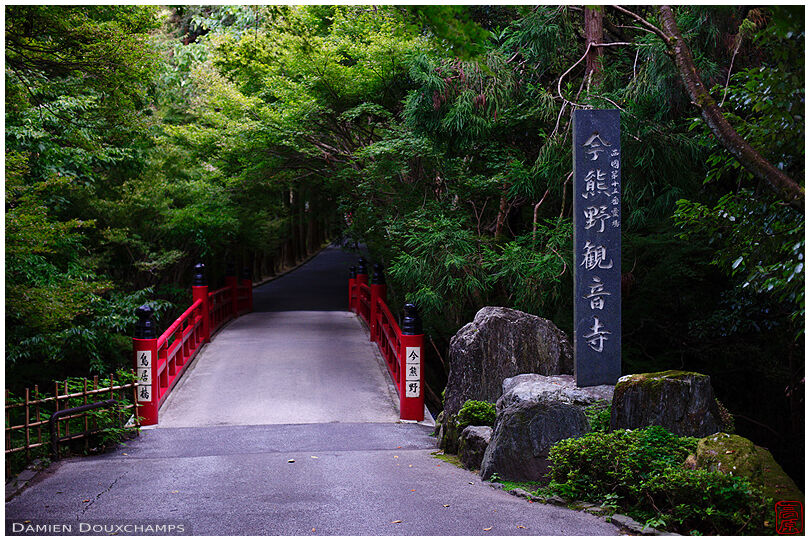 Red bridge in forest leading to Imakumano Kannon-ji temple