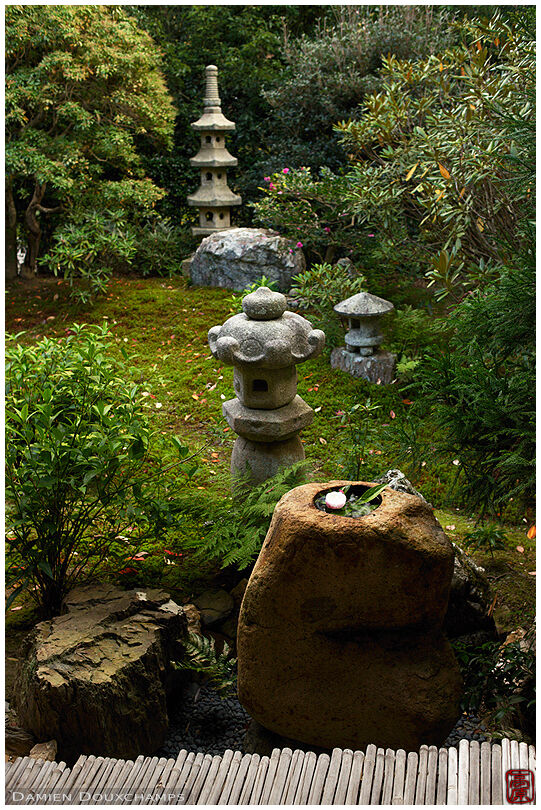 Stone lanterns and tsukubai water basin in moss garden, Jikishi-an temple