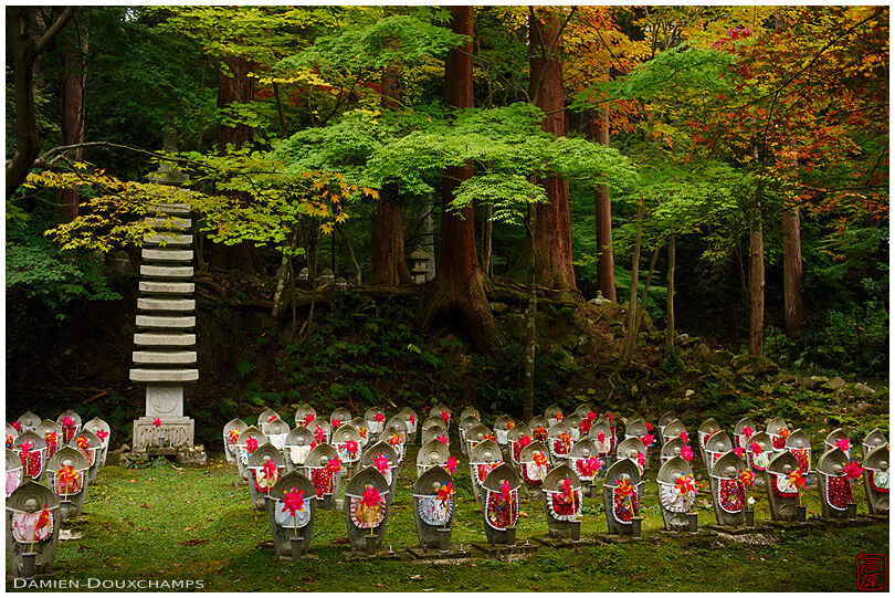 Jizo statues adorned with bibs and toy windmills in Kongorin-ji temple forest, Shiga, Japan