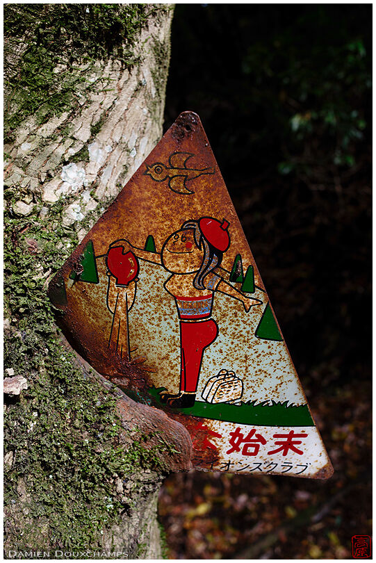 Old rusty fire prevention sign embedded in growing tree, Ohara, Japan