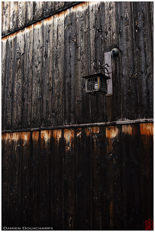 Old iron lantern on burned wood facade, Kyoto, Japan