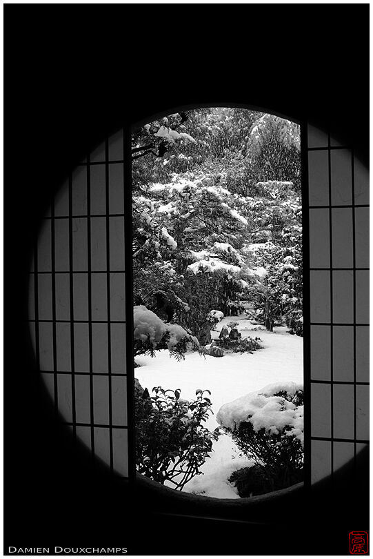 Round window on snowy Japanese garden, Funda-in temple, Kyoto, Japan