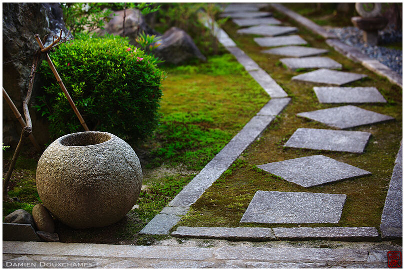 Round empty tsukubai basin and entrance path to a private residence in Kyoto, Japan