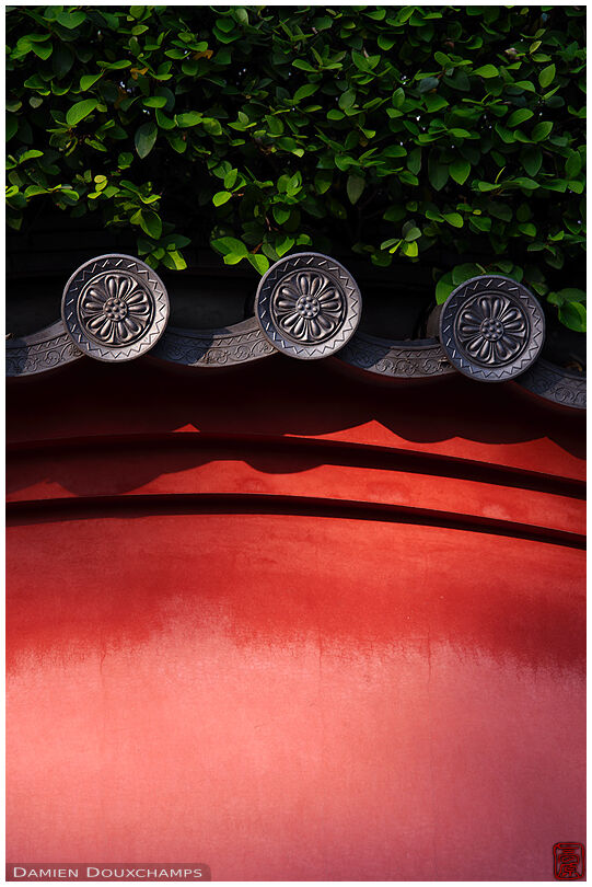 Red wall with elaborate tiles, Isshin-ji temple, Osaka, Japan