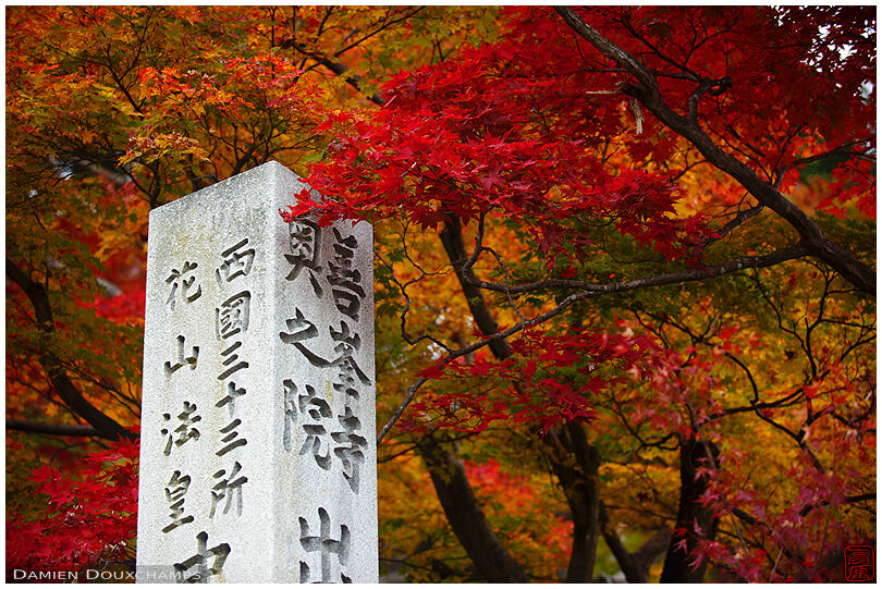 Autumn foliage around pillar marking the Okunoin section of Yoshiminedera temple, Kyoto, Japan