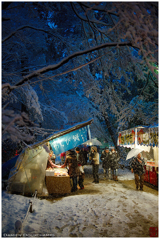 Food merchants along the entrance path to Shimogamo shrine on new year day during a snowstorm, Kyoto, Japan