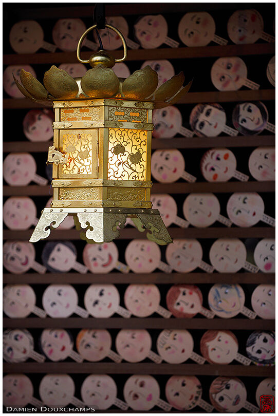 Golden lantern guarding humorous votive offerings, Kawai-jinja, Kyoto, Japan