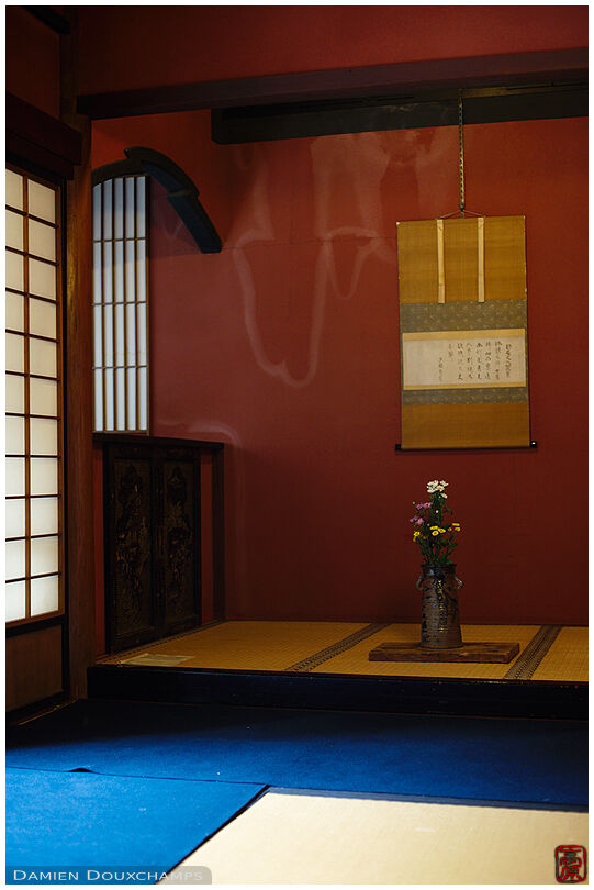 Red-walled tokonoma alcove with seasonal ikebana flower arrangement and scroll, Nobotoke-an, Kyoto, Japan