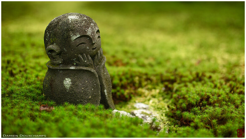 Little cute jizo statue amidst fresh green moss, Enko-ji temple, Kyoto, Japan