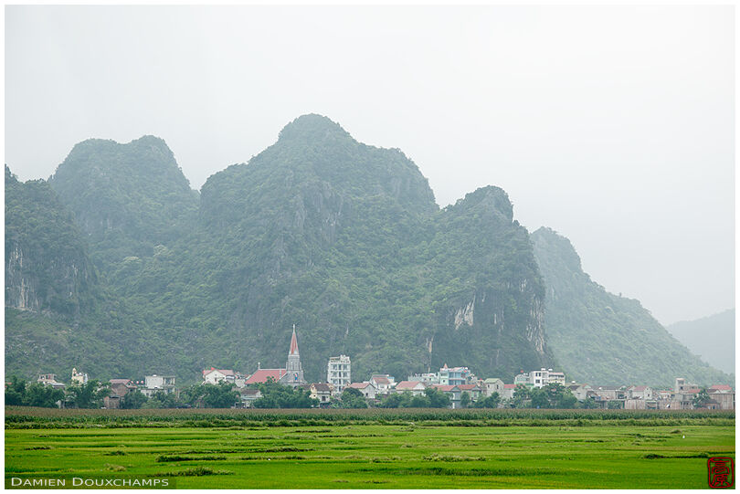 Village among impressive mountains as seen from the boat leading to Phong Nha cave, Vietnam