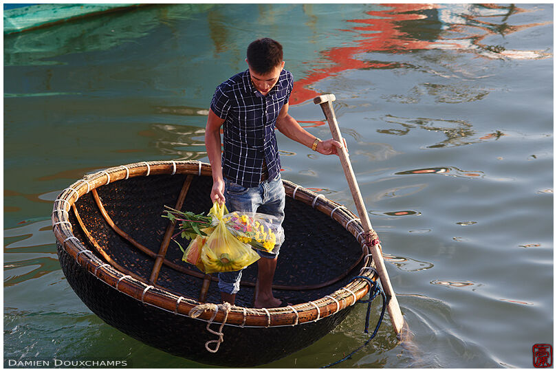 Man with shopping bags on round shuttle boat in Dong Hoi harbour, Vietnam