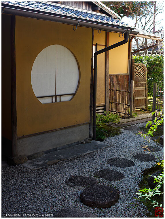Stepping stones passing by the round window of a tea house, Jisho-in temple, Kyoto, Japan