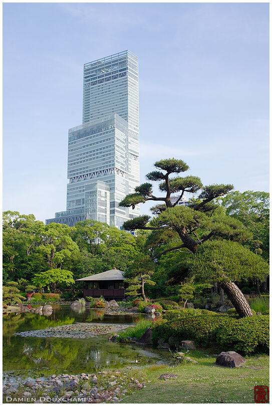 Tall modern tower overlooking the traditional Keitaku-en garden in Osaka, Japan