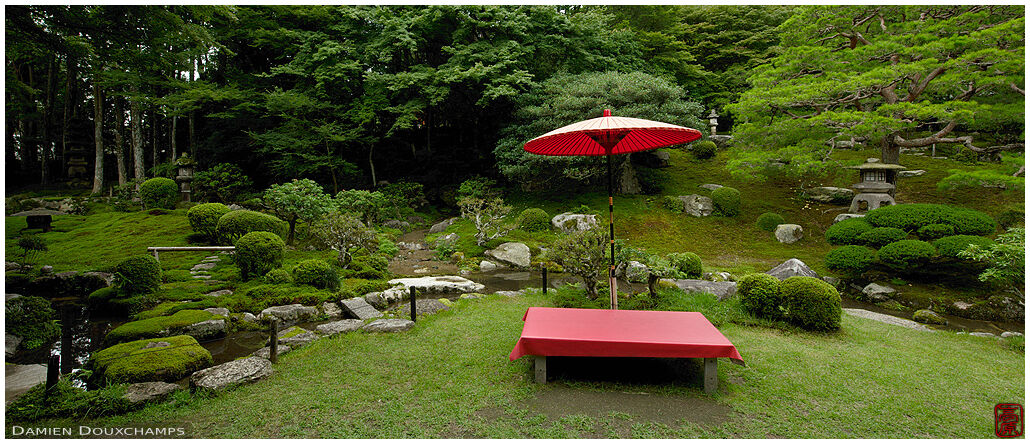 Seating bench with red traditional umbrella in the gardens of Chikurin-in temple, Shiga, Japan