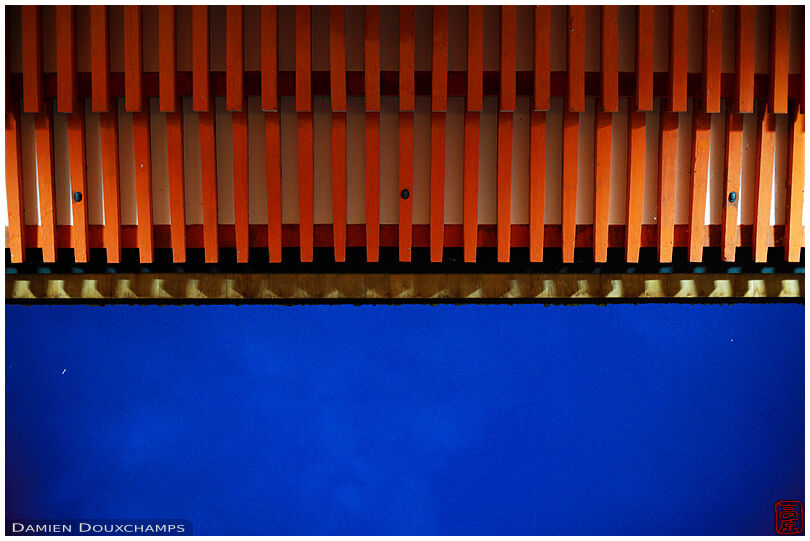 Red shrine gate roof lines contrasting with dark blue sky during the blue hour in Shimogamo shrine, Kyoto, Japan
