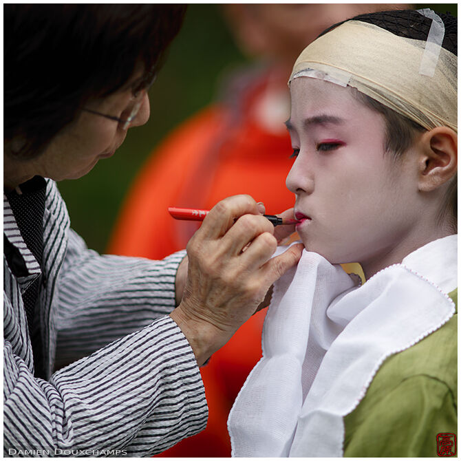 Child getting last touches of make-up before the start of the Jidai festival in Kyoto, Japan