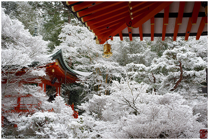 Golden bell, orange rooflines and white winter wonderland forest in Bishamondo temple, Kyoto, Japan