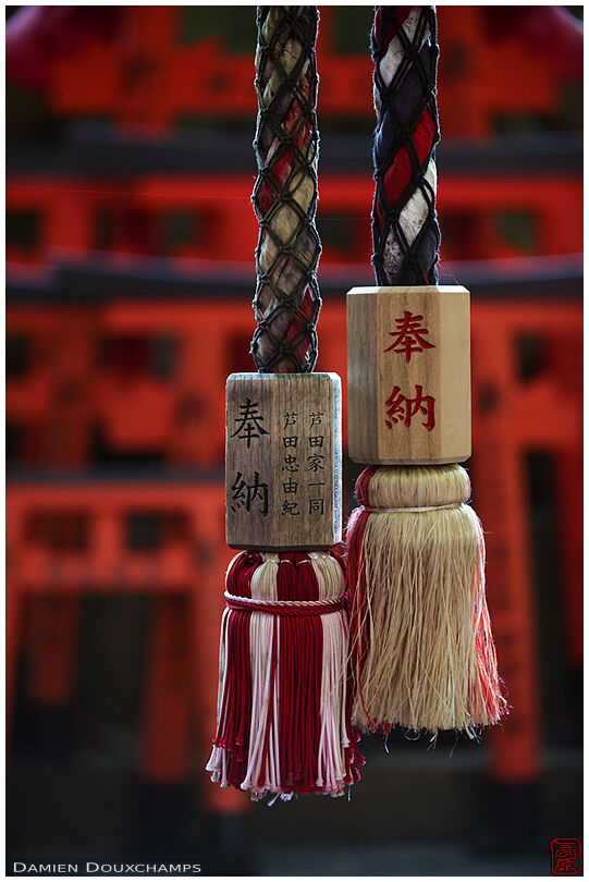 Two bell ropes in front of small torii gates, Fushimi Inari shrine, Kyoto, Japan