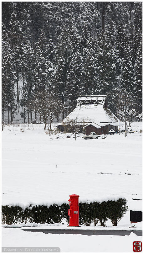 Red mail box amidst white snowy landscape in Miyama countryside village, Kyoto, Japan