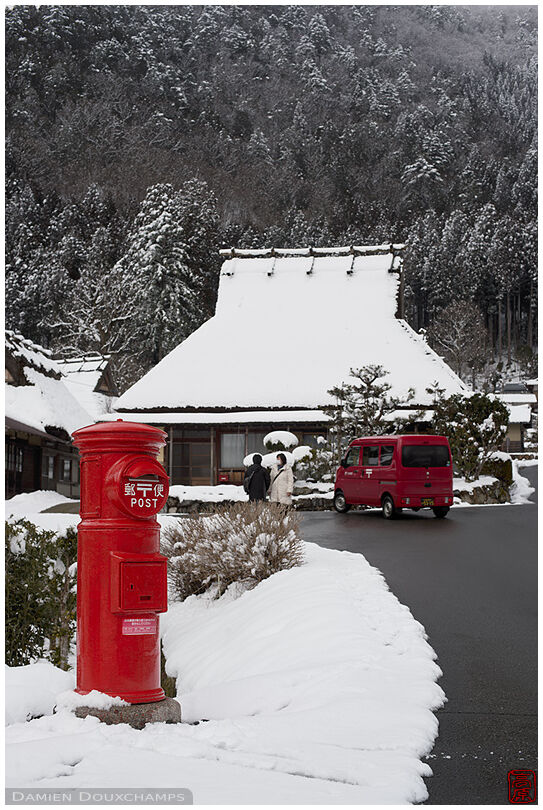 Cute old-style round post collection box and cute kei-car postal van in the snow covered village of Miyama, Kyoto, Japan