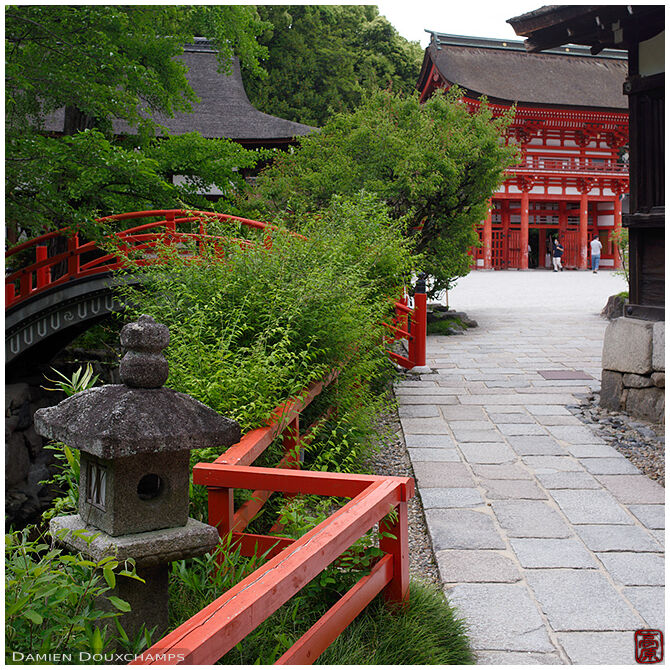Red curved bridge over small river on the grounds of Shimogamo shrine, Kyoto, Japan