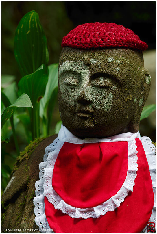 Mossy jizo statue with red knitted hat and bib, Okunoin cemetery, Koyasan, Japan