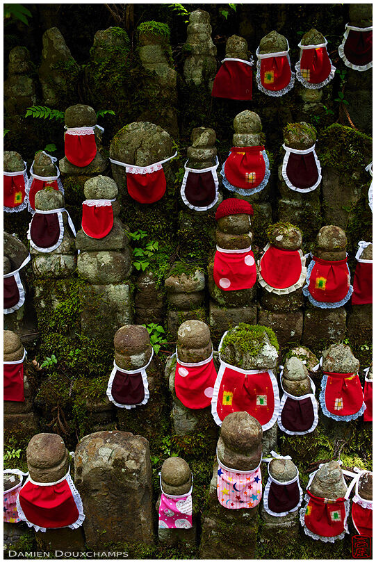 Old moss covered jizo with colorful bibs in the Okunoin cemetery of Koyasan, Wakayama, Japan