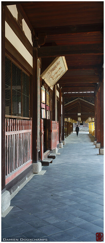 Lone visitor walking on a covered alley in the large expanse of Manpuku-ji temple grounds, Kyoto, Japan
