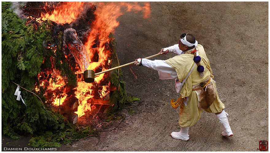 Throwing water on massive fire with giant ladle during festival in Tanukidani Fudoin temple festival, Kyoto, Japan