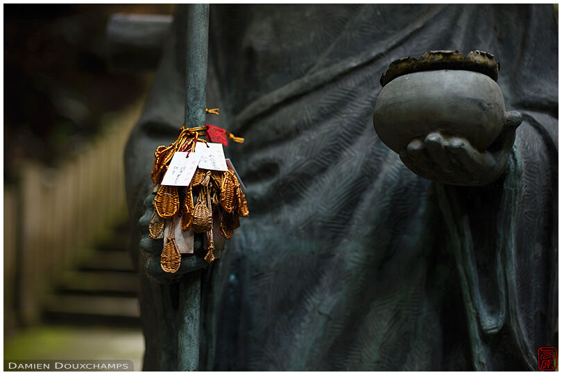 Pilgrim statue with little sandals as votive offerings in Tanukidani-san Fudō-in temple, Kyoto, Japan