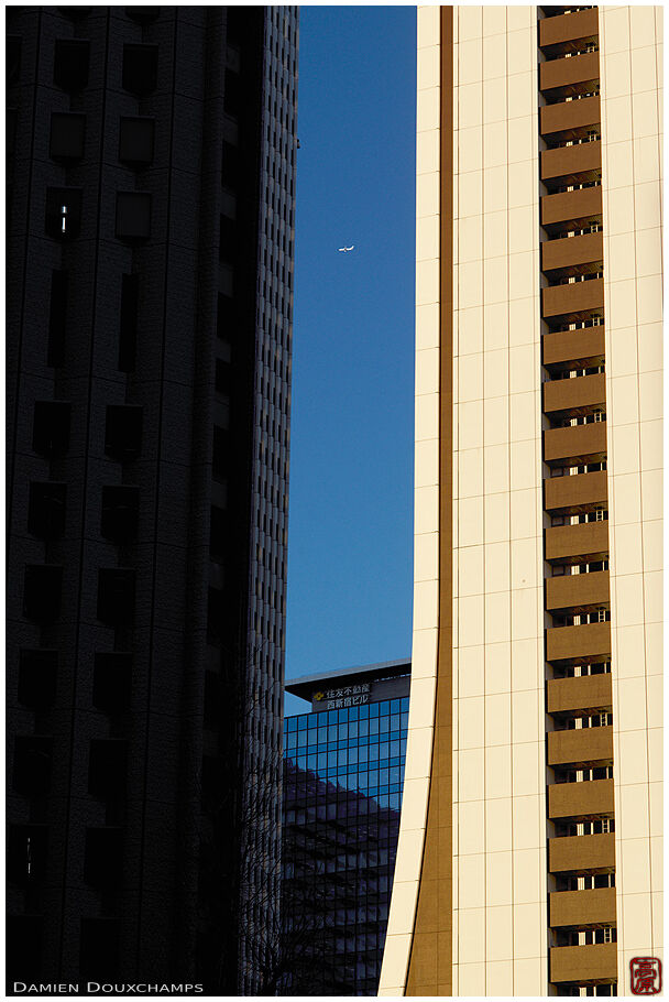 Airplane passing between tall buildings in the business district of Shinjuku, Tokyo, Japan