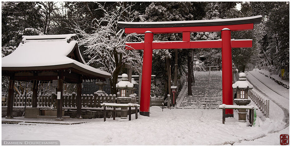 Red torii gate on a snowy day at the entrance of Yoshida shrine, Kyoto, Japan