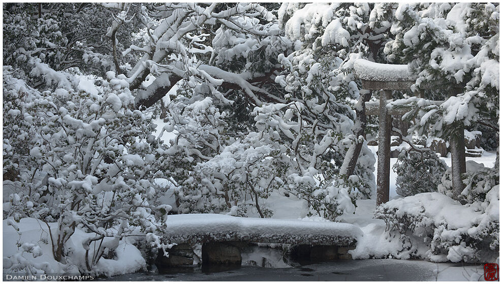 Stone torii hiding in show-covered pond garden, Konchi-in temple, Kyoto, Japan