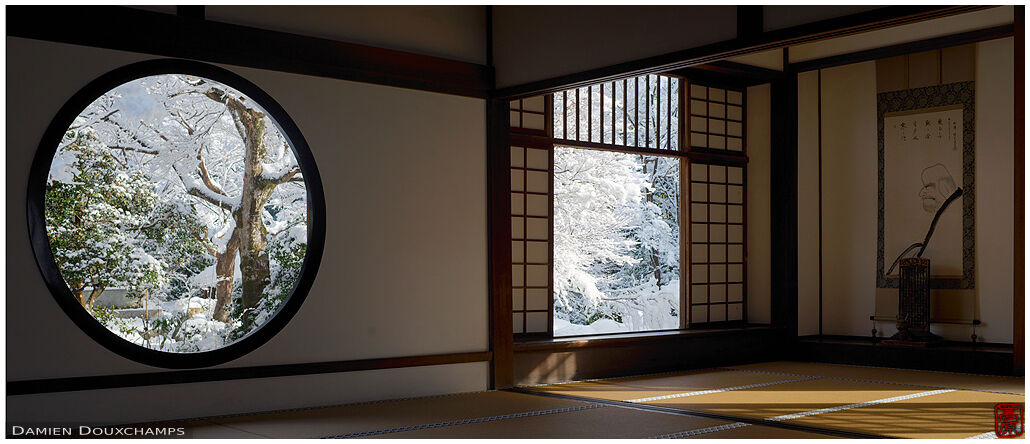 Snow covered trees seen through the round window of enlightenment and the square window of disillusion, Genko-an temple, Kyoto, Japan