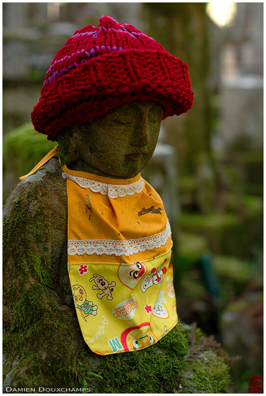 Mossy jizo statue with red hat and child bib, Okunoin, Koyasan, Japan