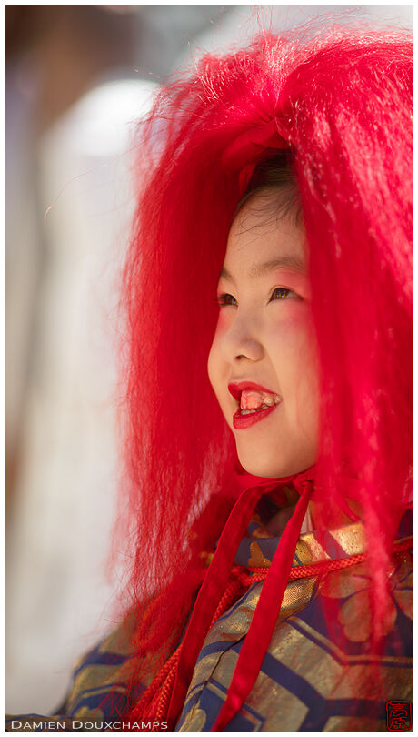 Child with red hair and red teeth during the Jida festival in Kyoto, Japan